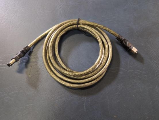 A coiled and twist-tied FireWire 400 cable on a blue background.