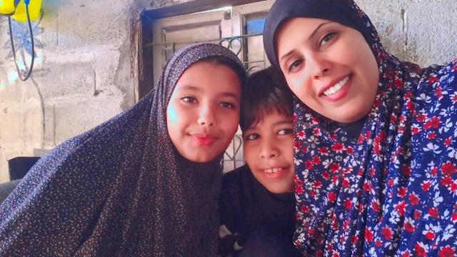 Three people smiling at the camera, a woman and two children.