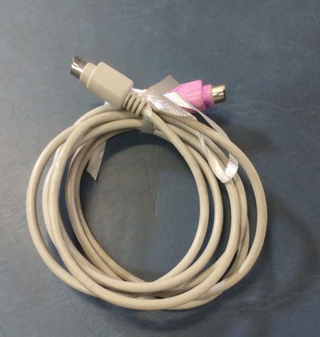 A gray cable coiled up and tied with a thin ribbon, lying on a blue background. It has two male mini-DIN connectors, one of which has been colored pink.