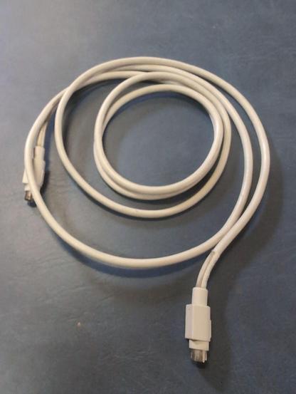A grey cable coiled on a blue background. It has male mini-DIN connectors on both ends. The outline of a symbol molded into the connector is visible on the underside, not the top where Apple molded the symbol or logo.
