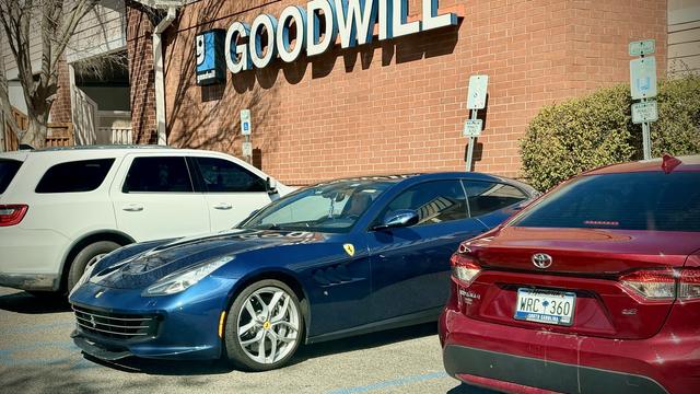 A beautiful blue Ferrari with a handicapped tag in handicapped parking outside a Goodwill.