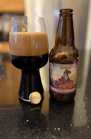 A stout glass is full of dark beer with a thick dark tan head. Then brown bottle shows a horse missing its rider in a mountain scene.