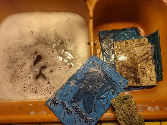 On évier dans lequel des blocs gravés bleu et beige sont nettoyés à l'eau et au liquide vaisselle