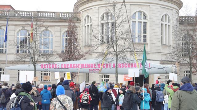 Auf dem Bild ist eine Menschenmenge zu erkennen. Die Menschen stehen mit Schildern vor einem Rotorblatt einer Windkraftanlage die von der NGO Campact vor das Wirtschaftsministerium in Berlin gebracht wurde, um unter dem Motto „Energiewende nicht verschrotten“ gegen die aktuelle Energiepolitik von Wirtschaftsministerin Katherina Reiche zu protestieren.