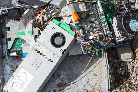 The insides of an old PC thrown on the ground outside. Weathered.