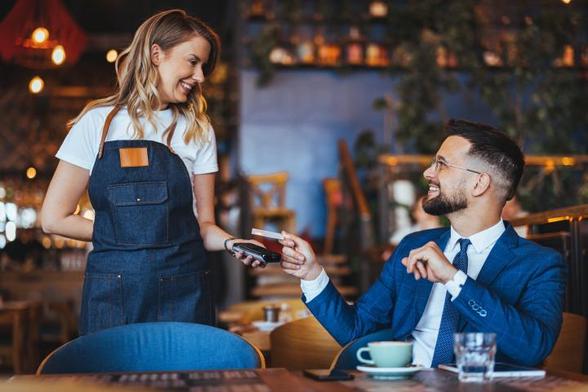 Un cliente vestido con traje, pagando en un restaurante. (Getty Images)