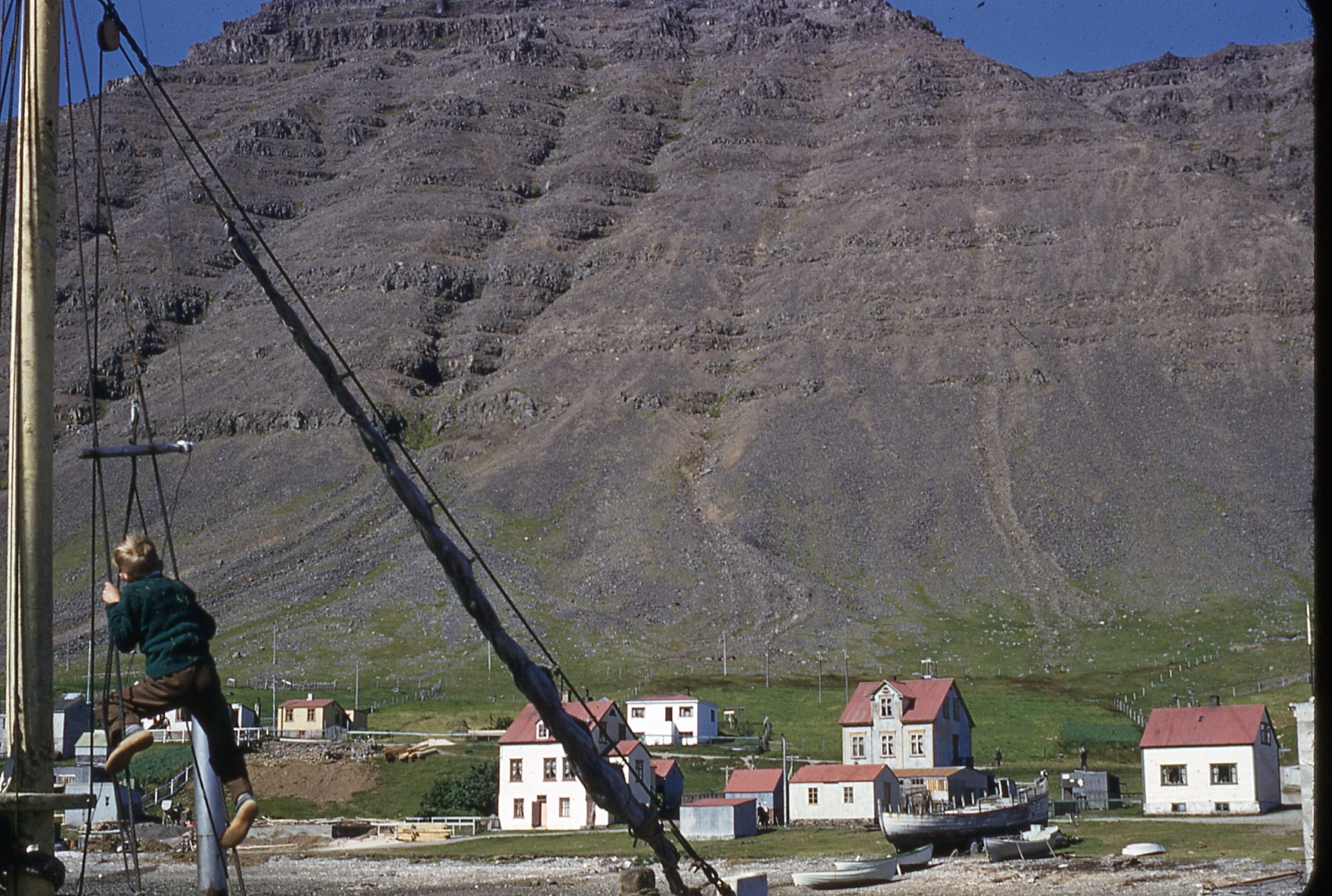 A small village next to a mountain and a boy climbing.