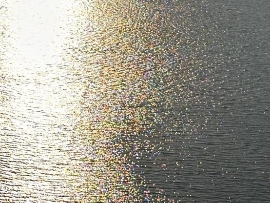 An iridescent shimmer on a calm river of blue gray water. My pic