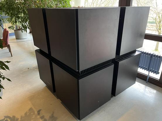 Blick auf eine Connection Machine schräg von der Seite. Sie besteht aus acht aneinandergesetzten schwarzen Würfeln. An einem Würfel ist schwach zu erkennen, dass die Abdeckung aus rot durchscheinendem Material besteht.