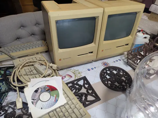 Two yellowed Macintosh 1MB computers, a matching mouse, and a bunch of accessories for a PowerMac G4