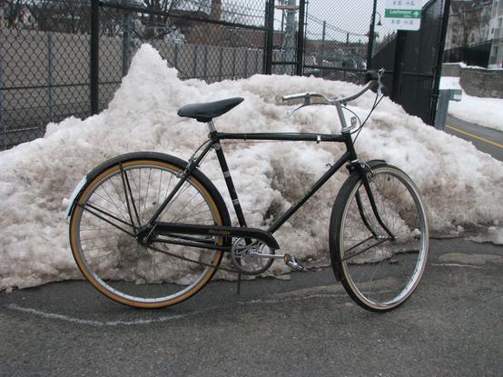 A black bike in front of a snow pile on the Community Path.