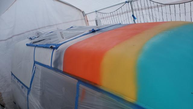 Blue, yellow, orange, and blue-grey sections painted on a hearse's vinyl roof.