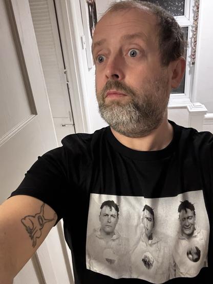 White middle aged man stares like he’s scared whilst rocking a brilliant triptych photo t-shirt of the legend Geoff Rushton aka Jhonn Balance of Coil fame. T-shirt made by the original photographer
