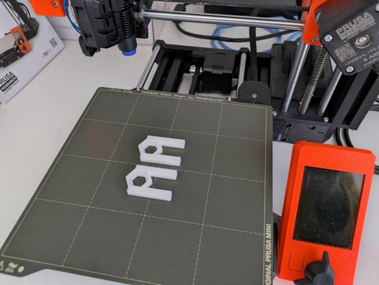 The bed of a Prussa Mini 3D printer with two real copies of the OpenSCAD design.