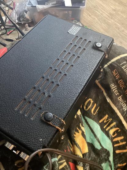 Leather backside of a 1969 ish radio, showing that the back opens up for access, and is held shut with nice straps with snaps.