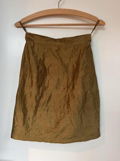 A short skirt in tulip silhouette, made of a warm olive green silk.