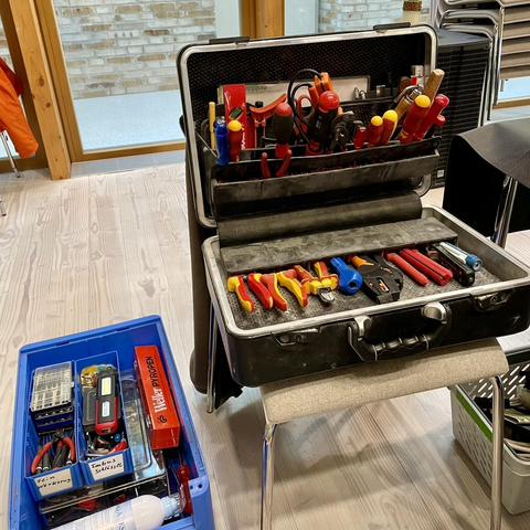 Aufgeklappter, schwarzer Werkzeugkoffer und blaue Plastikkiste mit Werkzeug.