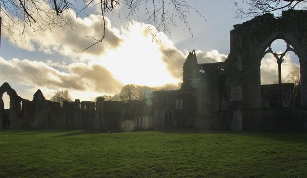 Wide shot of Netley Abbey, a stone ruin with sun and clouds