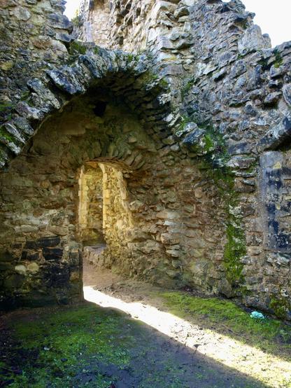The ruins of a doorway with sunlight streaming through in a narrow beam on the ground.