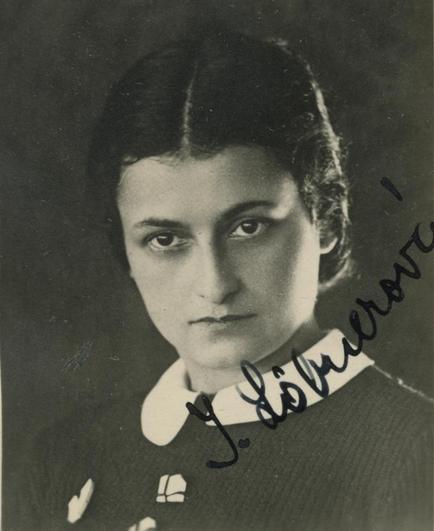Black and white portrait of a woman featuring a focused expression and a dark outfit with a light-colored collar.