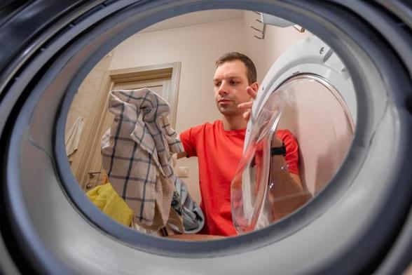Retrato de un hombre serio lavando ropa sucia en una lavandería. (rbkomar)