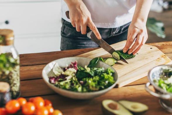 Una mujer cortando verduras en la cocina. Imagen de archivo (Getty Images)