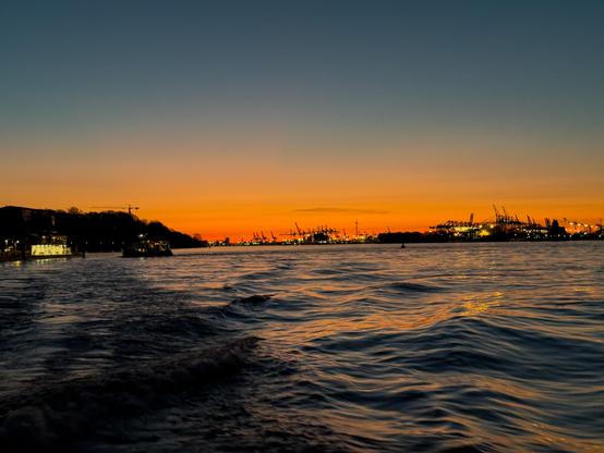 Sonnenaufgang über der Elbe, am Horizont die Hafenanlagen.