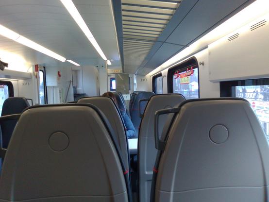 Photo taken inside a Caltrain car showing how a poster they put up blocks the view of a display that tells you what the next stop is.