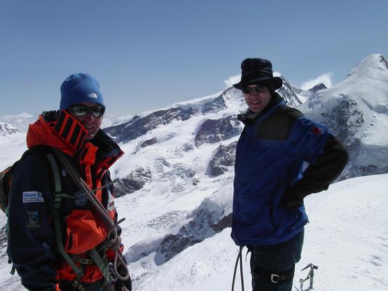 2 Personen auf einem Berggipfel, links in Rot der Bergführer, Rechts bin ich. Oben auf dem Pollux. Im Hintergrund eine Alpine Landschaft aus Schneebedeckten Bergen vor einem blauen Himmel