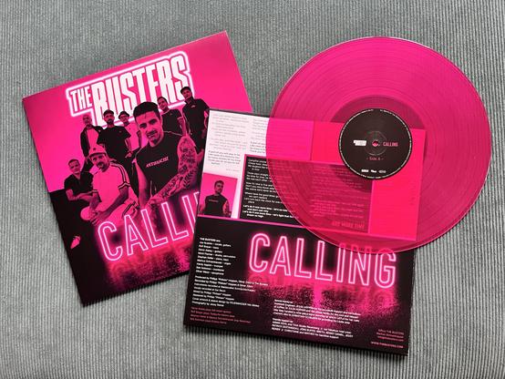Die leuchtend pinke und halbtransparente Colored Vinyl des neuen The Busters Albums “CALLING” – neben Hülle und Booklet.