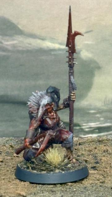 A heretic trooper kneels in the mud with a spear and sword.