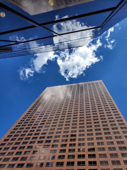 Looking up between two buildings in downtown Los Angeles, California.  The sky is blue with puffy white clouds.  The reflection of the sky hides the building in the top of the frame.

Henry David Thoreau reflected: "Though my life is low, if my spirit looks upward habitually at an elevated angle, it is as if it were redeemed."