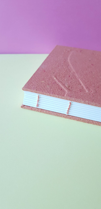 Zoom sur la reliure copte du carnet avec un fil rose assortie à la couverture