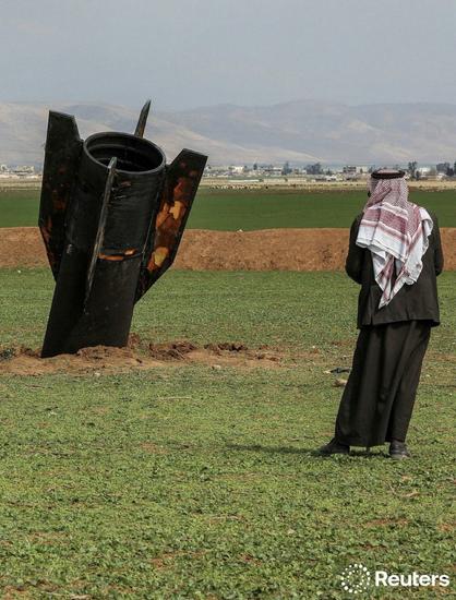 Large missile nose first in the ground with a man standing with his back turned looking at it