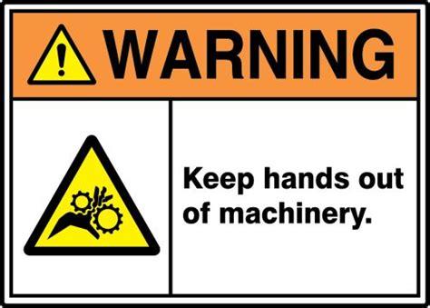 Warning sign of a stylized hand crushed by cogwheels. On the side it reads: "Keep hands out of machinery."