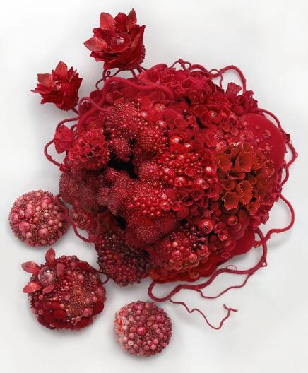 An intricate, all-red wall sculpture by Amy Gross of imaginative flora made from paper and beads