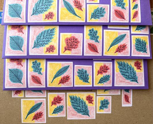 A set of envelopes that are covered with stickers that have illustrations of many leaves in red and green ink.