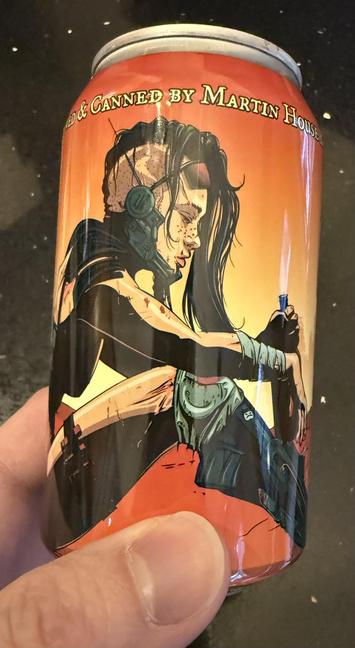 A beer can in shades of red and orange shows a cyberpunk woman with shaved hair, sunglasses, a radio headset, and shorts with chunky metal leg guards