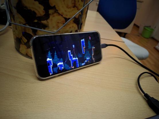 Fairphone 5 running Celeste, propped up on a table with a USB-C cable coming off of it.