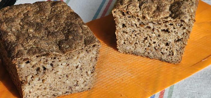 Ein Grahambrot in der Mitte aufgeschnitten mit sichbaren großen Poren, Vollkornbestandteil und Haferkörnern