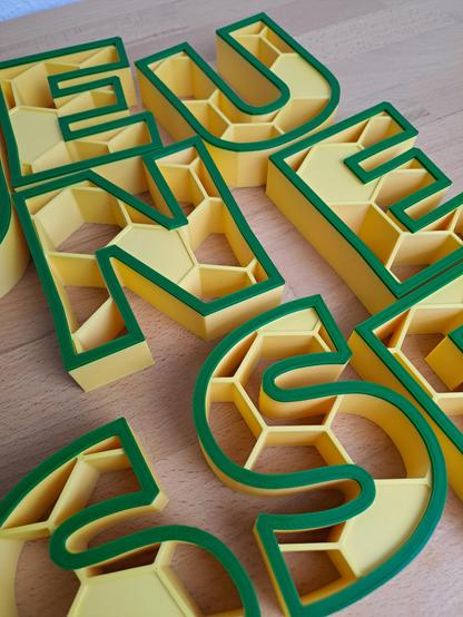 Les lettres du mot jeunesse imprimé en 3D jaune avec un motif en nid d'abeille et un contour vert foncé