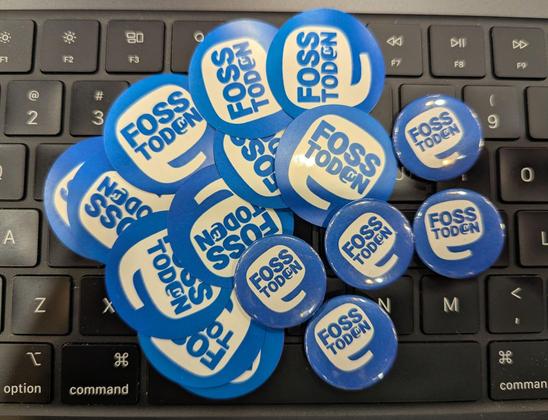 Fosstodon stickers and buttons on a laptop keyboard