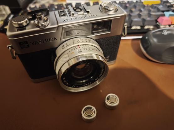 Le yashica electro 35 GX avec devant les deux piles bouton LR44 dans leur adaptateur leur donnent la forme de piles PX640