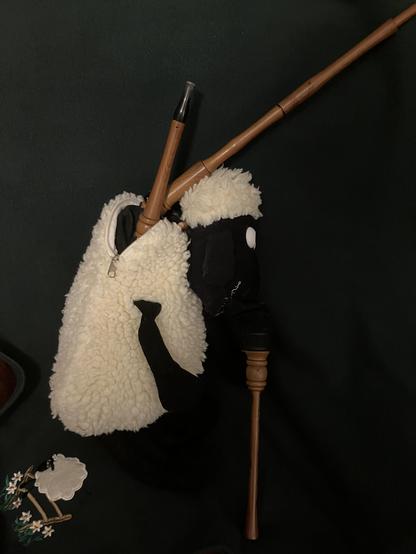 A Shaun The Sheep backpack, mutilated so a bagpipe chanter can stick out of the “mouth” while the single drone and blowpipe emerge from the zip, trying to create some sort of comedic “bock” effect