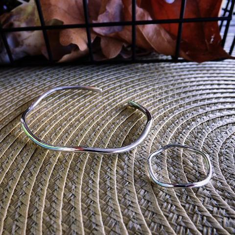 a wavy silver cuff bracelet and similar ring on a mat
