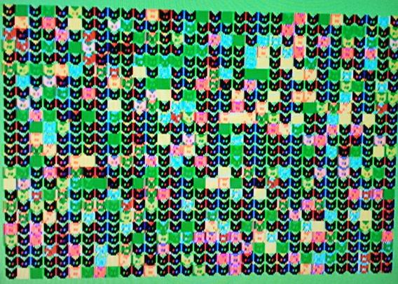 a rendition of the ti99 rainbow cats program showing a screen full of them, in random colors. the cats are text with a fg and bg color. many are uncolored yet in the code loop, so they're just black on green.