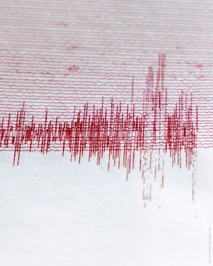 Nahaufnahme eines Seismogramms mit roten Zickzacklinien auf weiĂźem Papier.