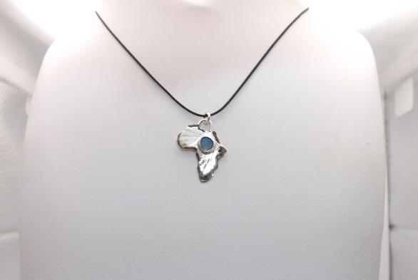 a silver pendant in shape of Africa! it has a light blue small gemstone in the middle and black cord