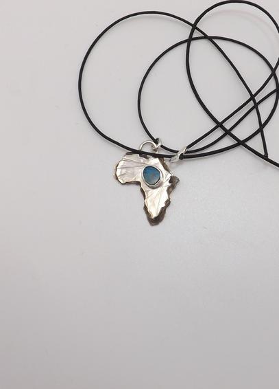 a silver pendant in shape of Africa! it has a light blue small gemstone in the middle and a tangled black cord