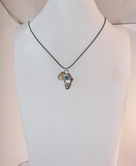 a silver pendant in shape of Africa! it has a light blue small gemstone in the middle and black cord. it's on a white bust